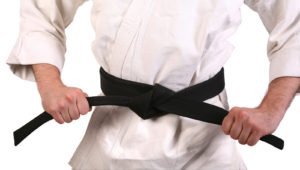 a martial arts student tying a black belt